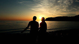 日落時分并肩坐在海灘邊的浪漫戀人